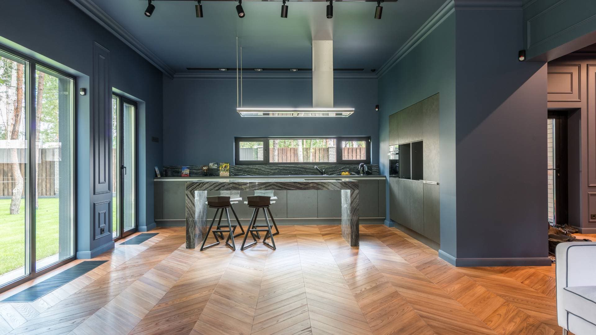 Open-plan kitchen in deep blue with a herringbone timber floor
