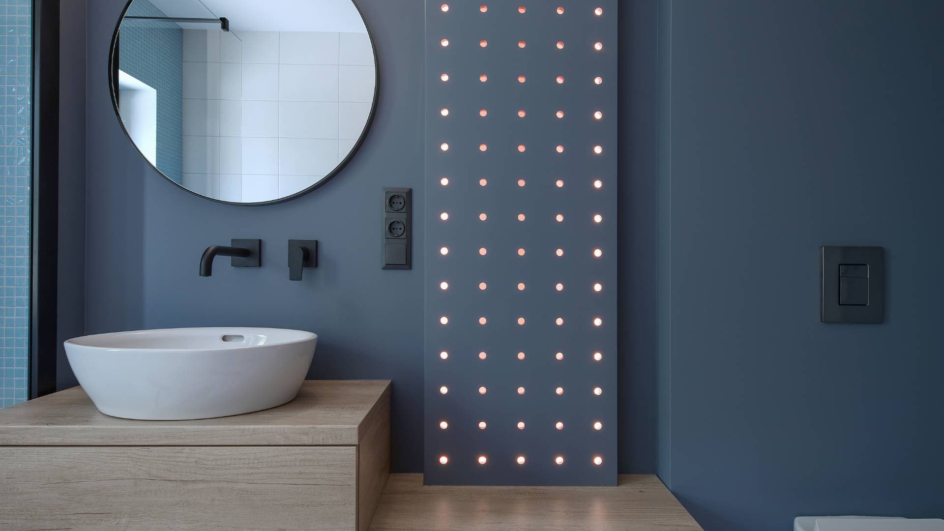 Bathroom feature wall in navy with a round mirror and vessel basin
